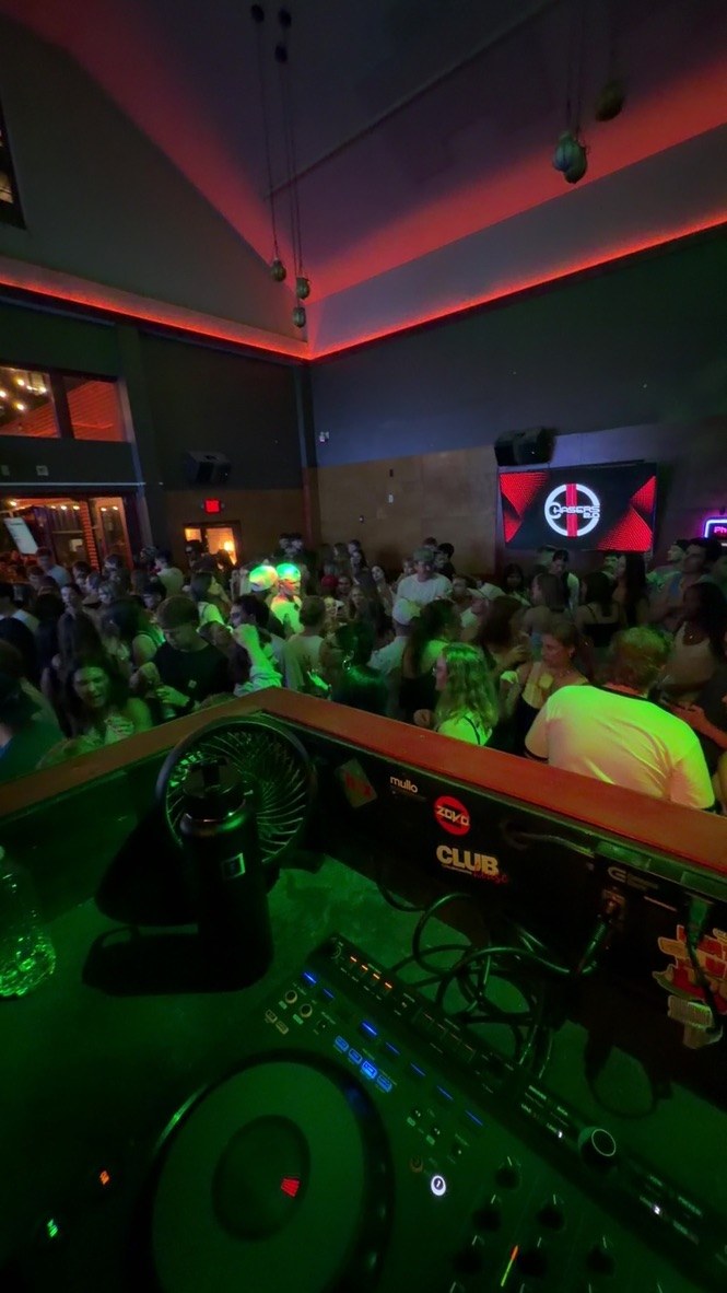 Green-lit crowd seen from the DJ booth