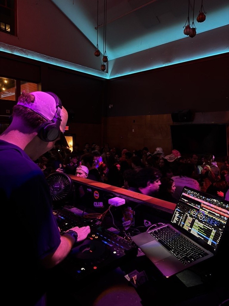 BENGAL in headphones with a laptop running a set over a full bar
