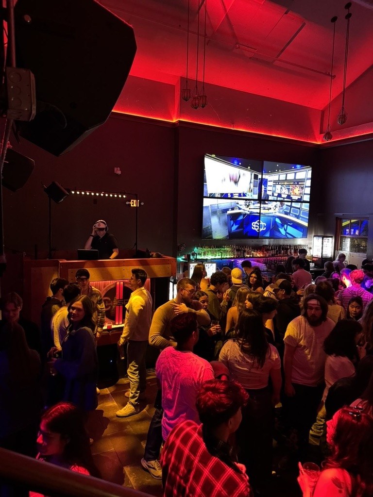 Packed bar dance floor under red lighting
